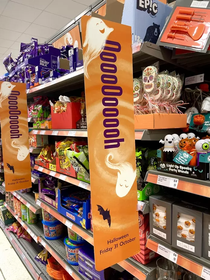 signage for Waitrose with hand illustrated ghosts and bats on an illustrated orange background 